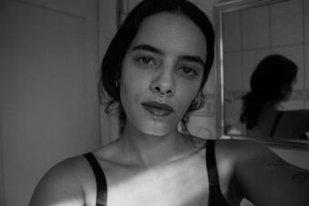 Artistic black and white selfie of a young woman with a nose ring, capturing dramatic shadows.